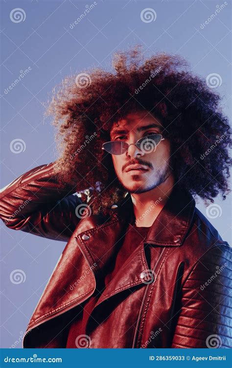 Portrait Of A Stylish Man With Curly Hair On A Blue Background