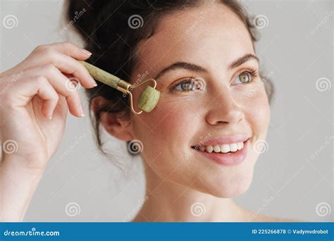 Half Naked Brunette Woman Massaging Face With Jade Roller Stock Photo