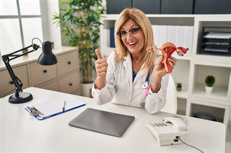 Middle Age Blonde Gynecologist Woman Holding Anatomical Model Of Female Genital Organ Smiling