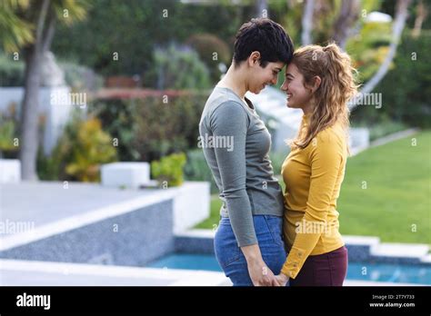 Happy Biracial Lesbian Couple On Garden Terrace Holding Hands And Touching Heads Copy Space