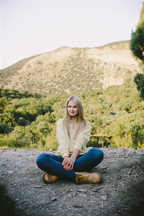 Jonge Blonde Vrouwenzitting Openlucht Op Een Achtergrond Van Bergen Stock Afbeelding Image Of