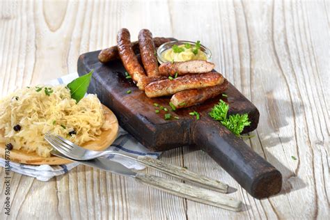 Nürnberger Rostbratwürste mit Senf auf einem rustikalen Steakbrett mit