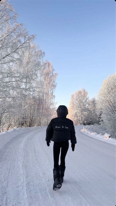 A Person Walking Down A Snow Covered Road In The Middle Of Winter With