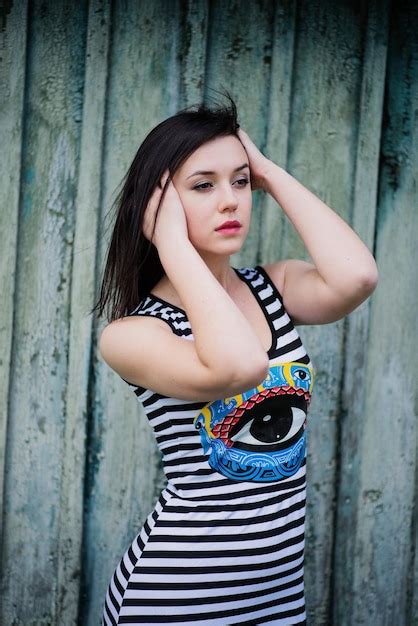 Brunette vorbildliches Mädchen am Kleid mit Streifenhintergrund cian hölzernem Hintergrund