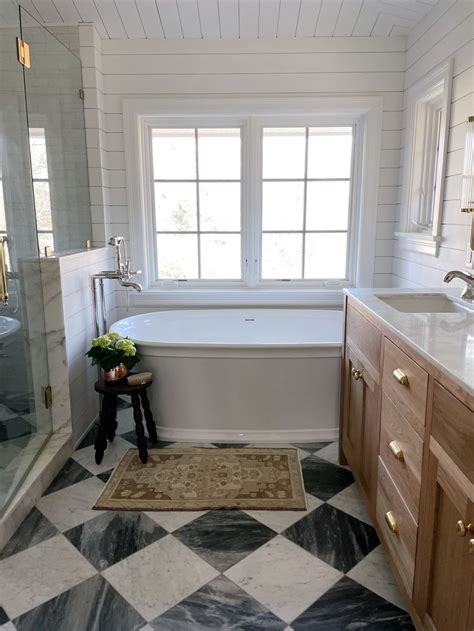 A White Bath Tub Sitting Next To A Window In A Bathroom On Top Of A