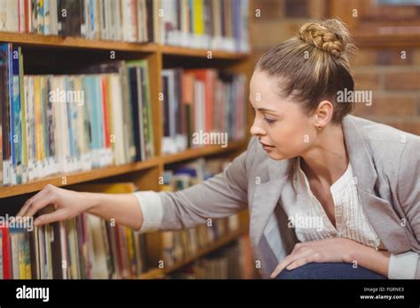 Blonde Teacher Searching Book In The Library Stock Photo Alamy
