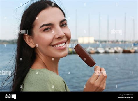 Beautiful Young Woman Holding Ice Cream Glazed In Chocolate Near River