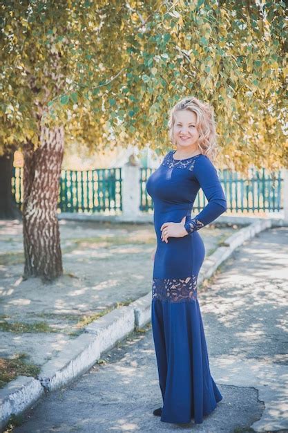 Premium Photo Beautiful Slim Blonde With A Long Blue Dress Smiles Under Autumn Tree