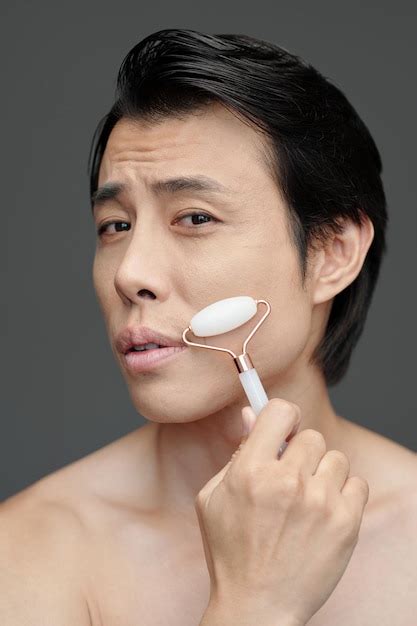 Premium Photo Man Massaging Face With Roller
