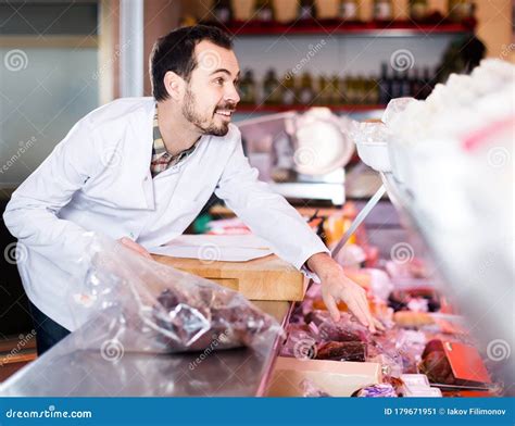 Male Shop Assistant Demonstrating Sliced Bacon In Butcherâ€™s Shop