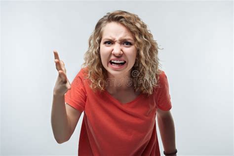 Angry Blonde Girl In Casual T Shirt Raising Hand Furious At Camera Rage And Aggressive Concept