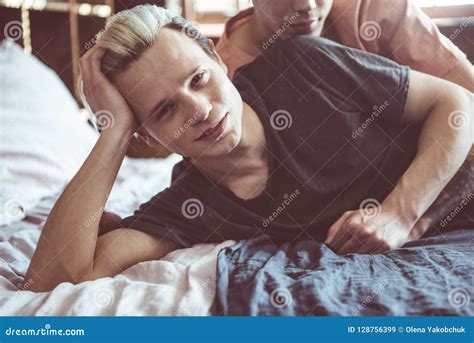 Pares Gay Jovenes Que Abrazan Mientras Que Descansa En Dormitorio En Casa Imagen De Archivo