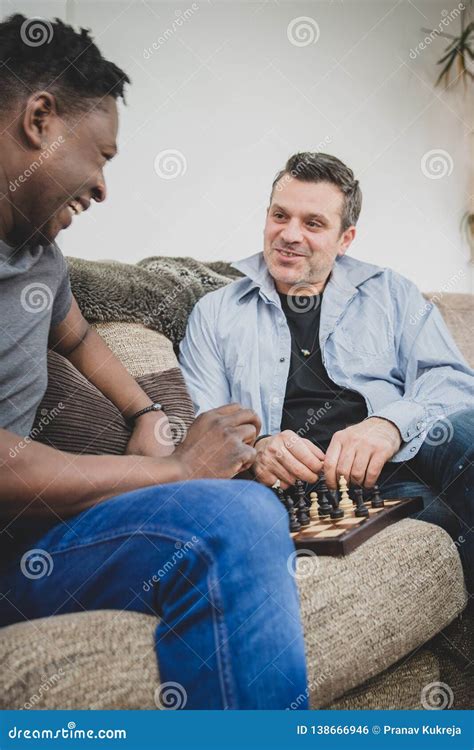 Un Par Gay Que Disfruta De Tiempo Dentro En Casa Jugando A Ajedrez Foto De Archivo Imagen De