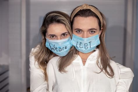 Premium Photo Lgbt Lesbian Couple In Medical Protective Masks With Sign On Faces Love Women