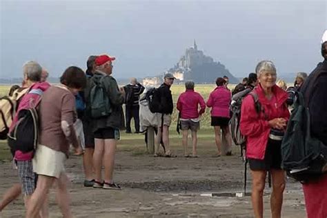 pelerins pieds nus dans la baie pour rejoindre le mont saint michel