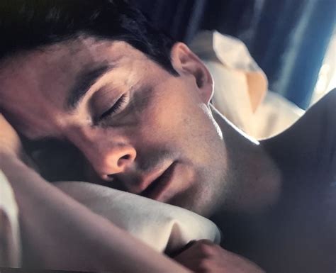 A Man Laying In Bed With His Eyes Closed And Head Turned To The Side As