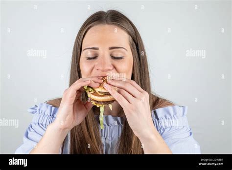 Portrait Of A Beautiful Young Woman Eating A Burger Isolated On White