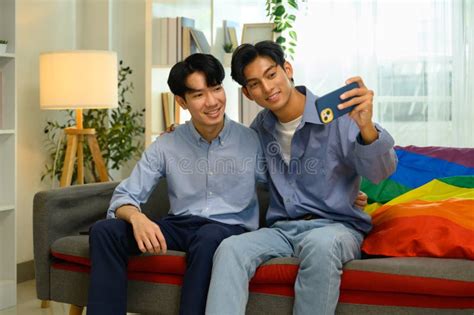 Happy Smiling Gay Couple Taking A Selfie Together With Smartphone On Sofa At Home Stock Image