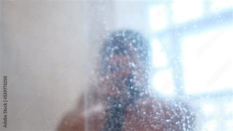 Rear view of a naked woman washing her hair with shampoo while taking a shower vídeo do Stock
