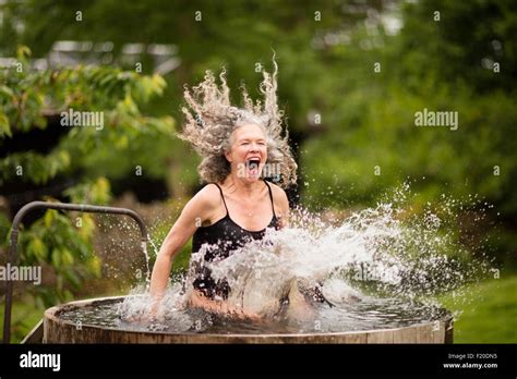 Mature Woman Splashing Into Fresh Cold Water Tub At Eco Retreat Stock Photo Alamy