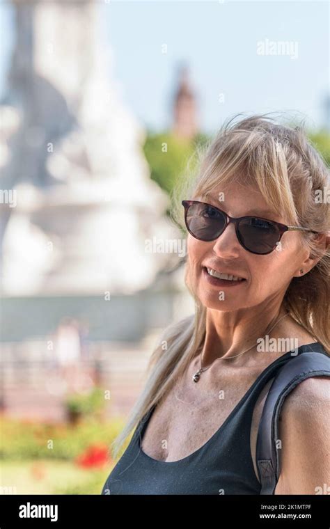Vertical Photo Of Mature Blonde Woman With Glasses Looking At The Camera Behind Out Of Focus