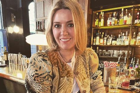 a woman sitting at a bar with a glass in front of her and bottles ...