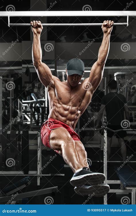 Muscular Man Working Out In Gym Doing Stomach Exercises On A Horizontal Bar Strong Male Naked