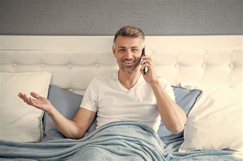 Premium Photo Glad Mature Man In Bed Speaking On Phone