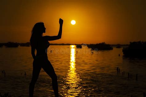 A Lovely Nude Latin Model Is Silhouetted As She Poses With The Rising Sun Behind Her On A