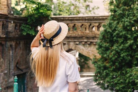 Une Minuscule Fille Blonde Aux Cheveux Longs En Robe Blanche Se Tient Le Dos à La Caméra Et