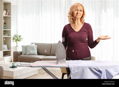 Bored Mature Woman Holding An Iron Inside A Living Room Stock Photo Alamy