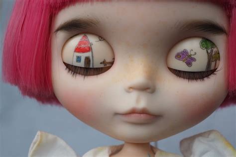 The Doll Has Pink Hair And Is Wearing An Outfit With Small Houses On It