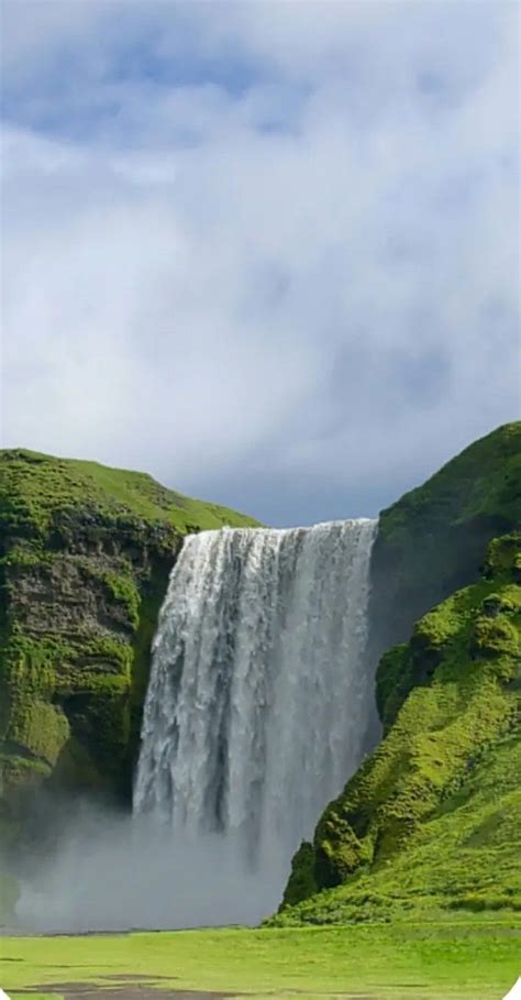 A Large Waterfall In The Middle Of A Lush Green Field