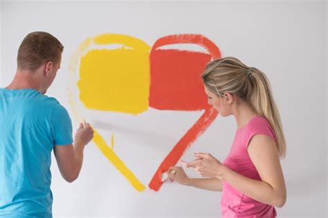 Una joven pareja feliz está pintando un corazón en la pared mientras