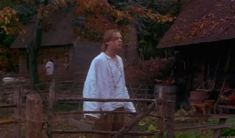 A Man Standing In Front Of A Wooden Fence