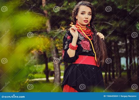 Brunette Girl In A White Ukrainian Authentic National Costume And A Wreath Of Flowers Is Posing