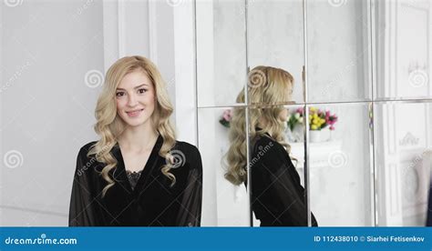 Blonde Female Model With Curly Hair In Black Negligee Is Smiling Near Mirror Stock Footage
