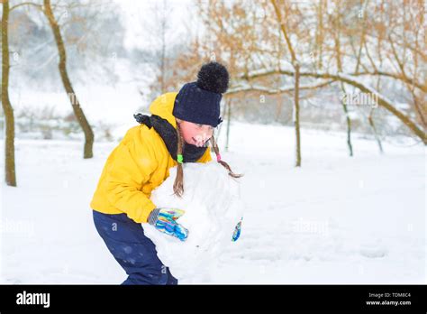 Little Girl Sculpts Snowman The Kid In The Yellow Jacket Is Carrying