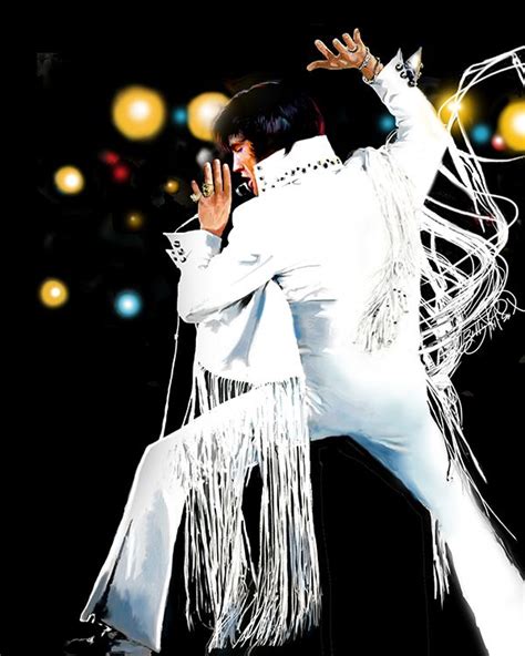 Elvis Presley Performing On Stage With His Hands In The Air While Wearing White Fringes