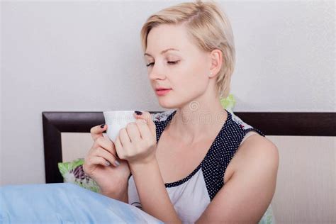 Jeune Belle Fille Blonde Avec Les Cheveux Courts Se Reposant Sur Son Lit Et Tenant Une Boisson