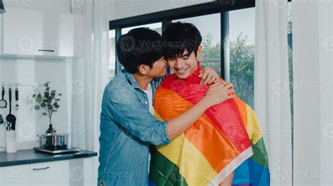 pareja gay asiática de pie y abrazos habitación en casa jóvenes guapos hombres lgbtq besándose