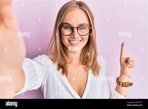 Schöne blonde Frau ein Selfie Foto trägt Brille lächelt mit einer Idee oder Frage zeigt