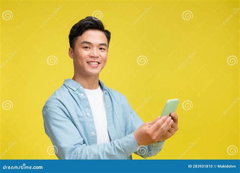 Portrait Of Young Handsome Asian Man Using Mobile Phone And Smiling