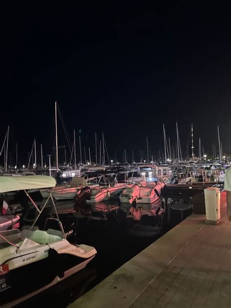 Many Boats Are Docked In The Water At Night Time With Lights On And Off