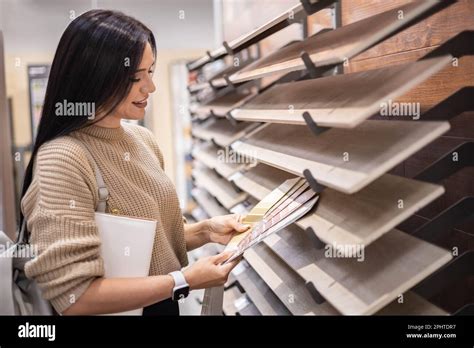 Happy Brunette Female Interior Designer Choosing Flooring Tile Color Texture Samples At Store