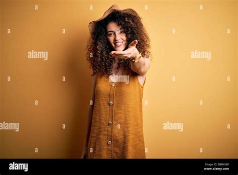 Beautiful Brunette Woman On Vacation With Curly Hair And Piercing Wearing Hat And Dress Smiling