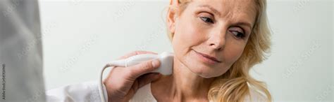 Doctor Doing Neck Examination Of Blonde Mature Woman With Ultrasound Banner Stock Photo