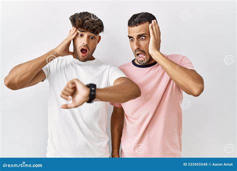 Pareja Joven Gay Parado En Un Entorno Aislado Mirando El Reloj Temeroso De Llegar Tarde Foto De