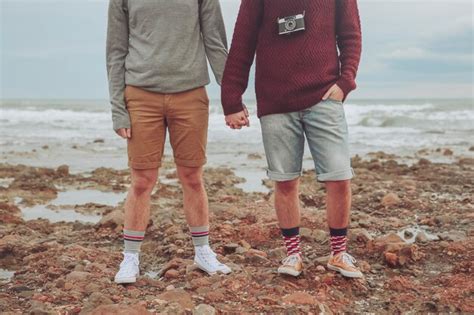 Pareja gay joven posición tomados de la mano en la playa vista parcial Foto Premium
