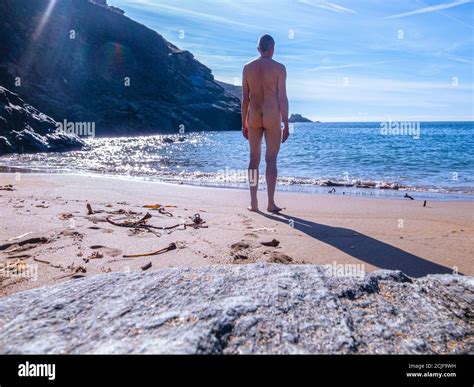 Back View Of A Fit Naked Man Looking Out To See From A Lonely Deserted Sandy Beach On A